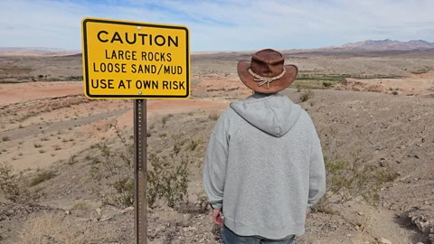 Exploring a rugged desert landscape with caution signs and a scenic view in.. Stock Footage 296497247