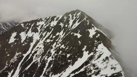 Exploring rugged snowy mountain terrain with a low flight Stock Footage 316802138