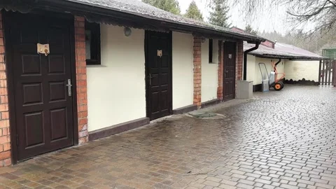 Exploring a rustic building with brown doors and cobblestone paths in a forest s Stock Footage 329906162