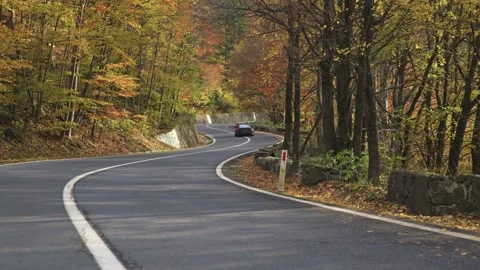 Exploring a scenic winding highway by car, surrounded by vibrant fall Video stock 330770359