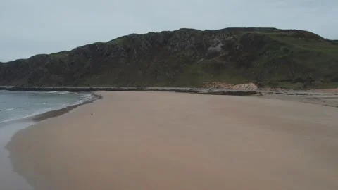 Exploring a serene beach with rocky cliffs and gentle waves in Donegal Stock Footage 310240358