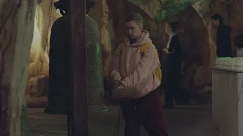 Exploring a serene cave with a large bell at an ancient site Stock Footage 312242753