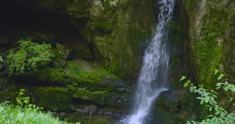 Exploring a serene waterfall surrounded by lush greenery in a tranquil landscape Stock Footage 314111981