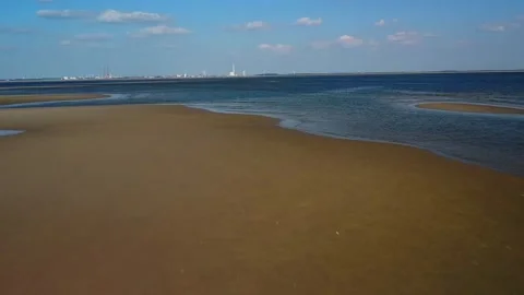 Exploring the shoreline at low tide with distant city skyline and blue sky Stock Footage 339940647