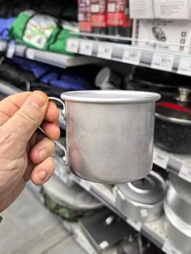 Exploring a store while holding a shiny tin cup in a modern kitchen section Stock Photos