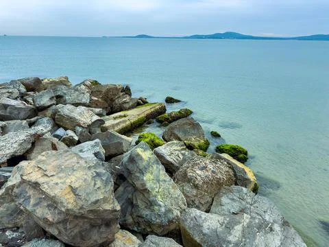 Exploring the tranquil shoreline with rocky formations and distant islands .. 스톡 사진