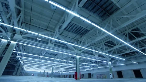 Exploring the vast empty warehouse illuminated by bright overhead lights Stock Footage 310909026