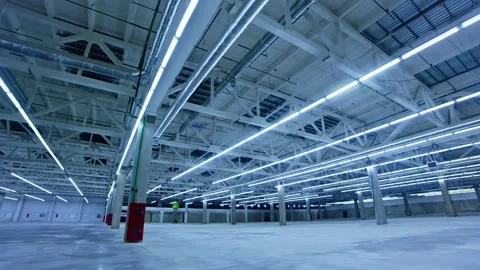 Exploring the vast empty warehouse illuminated by bright overhead lights Stock Footage 312118135