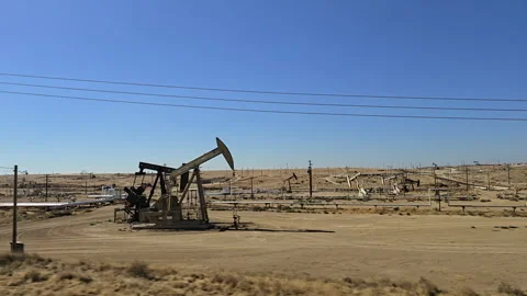Exploring the vast oil fields in a desert landscape under a clear blue sky Stock Footage 296497547