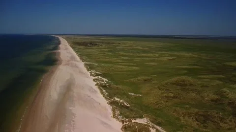 Exploring a wide sandy beach with grass and clear blue skies in a coastal l.. Stock Footage 339937512