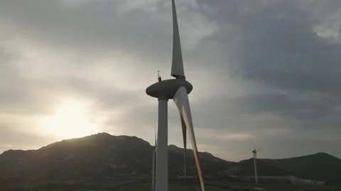 Exploring wind turbines against a sunset backdrop in a remote landscape Stock Footage 309426133