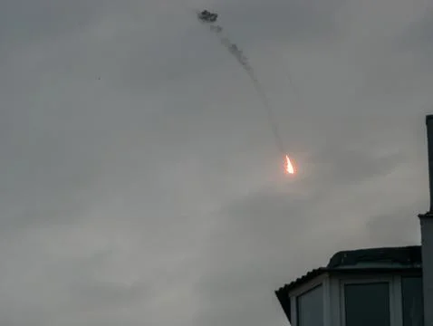 Explosion and fire trail of intercepted kamikaze drone in evening sky Stock Photos