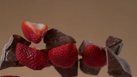 Explosion of chocolate chunks and sliced ​​strawberries. 4K footage Stock Footage 232317084