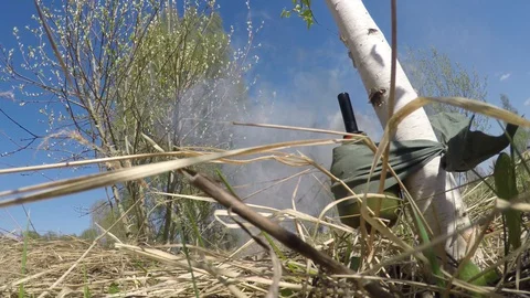 An explosion of a grenade tied to a tree trunk disguised among grass 스톡 동영상 128731748