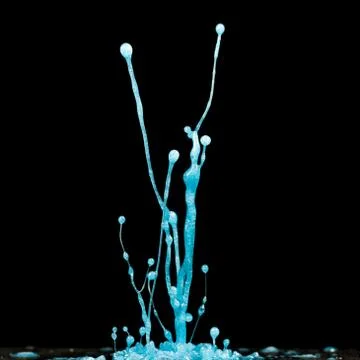 Explosion of splashes and bursts of colour fluid paint or ink on a black back Stock Photos