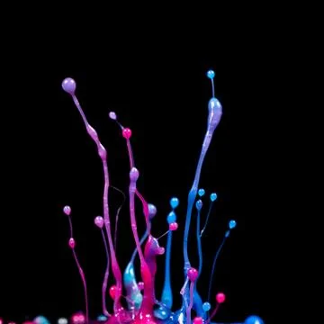Explosion of splashes and bursts of colour fluid paint or ink on a black back Stock Photos