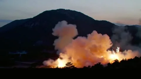 Explosions erupted across the valley below Mountain Stock Footage 315379049