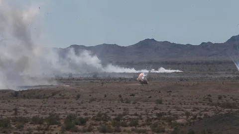 Explosions from helicopter during live fire exercise in desert 動画素材 106928680