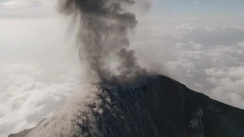 Explosive ash eruption at Fuego Volcano sending dark plume above clouds in Stock Footage 331054317