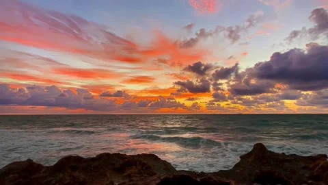 Explosive Ocean Sunset Sky Reflected on Raging Waves and Coastal Rocks Stock Footage 320040565