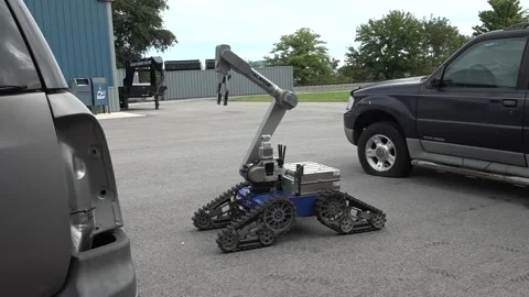 An explosive ordnance disposal robot moving into position to open a car door Stock Footage 284217634