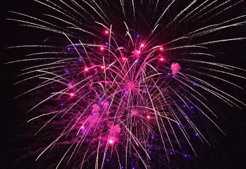 Explosive pink fireworks light up the night sky with sparkling trails Stock Photos