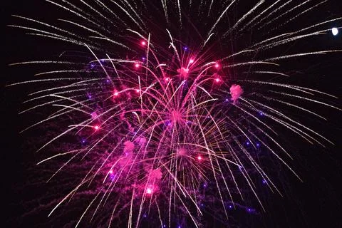 Explosive pink fireworks light up the night sky with sparkling trails Stock Photos