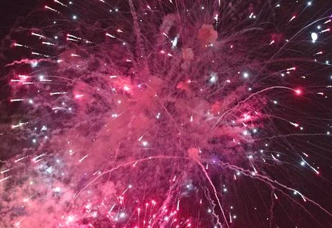 Explosive pink fireworks light up the night sky with sparkling trails Stock Photos