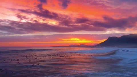 Explosive Red and Orange Sunset Over Mountain Coastline with Crashing Surf Stock Footage 320034872