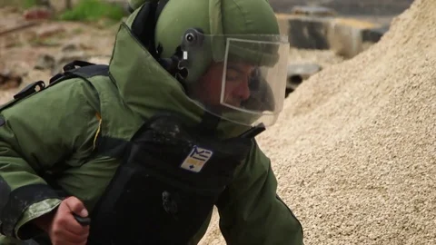 Explosives expert wearing protective suit mark IED with spray paint Stock Footage 91689230