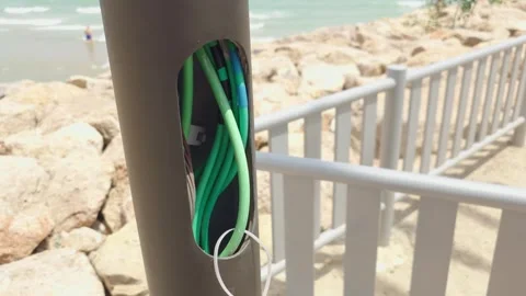 Exposed electrical wires inside damaged streetlight pole along seaside promenade Stock Footage 341952511