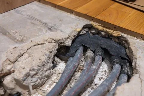 Exposed heating pipes emerging from a damaged concrete floor Stockfoto's