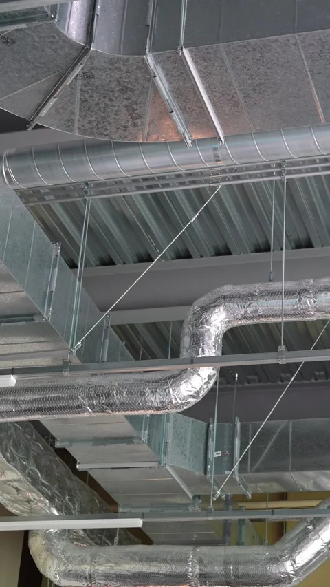 Exposed HVAC ductwork and silver pipes on industrial ceiling Stock Footage 345795880