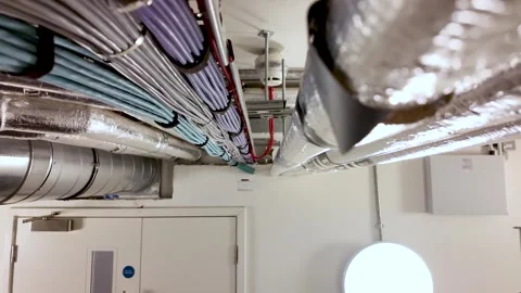 Exposed Metal Ductwork and Network Cables Running Along the Ceiling of a Stock Footage 327830452