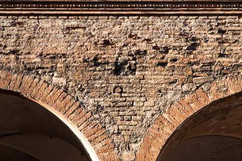 Exposed red bricks on the facade of an unrestored historical building with an Stock Photos