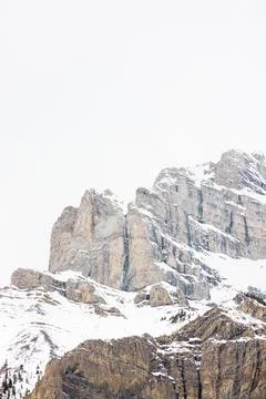 Exposed rock face mountain range covered in cold snow Stock Photos