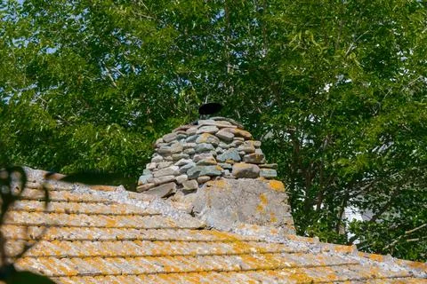 Exposed stone chimney on a rustic building surrounded by vibrant green trees Stock Photos