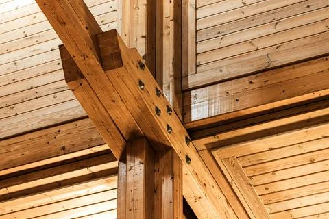 An exposed timber frame ceiling showcasing intersecting heavy wooden beams Stock Photos