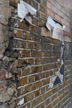 Exposed weathered brick wall with torn street posters. Foto stock