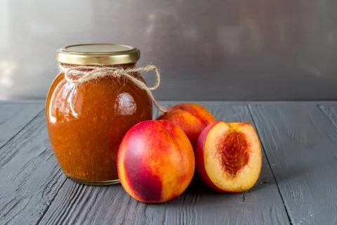 An exposition of jam pot with appetizing peaches on the wooden table Stock Photos