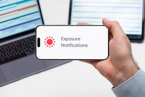 Exposure Notifications application logo on the screen of smart phone in mans Stock Photos
