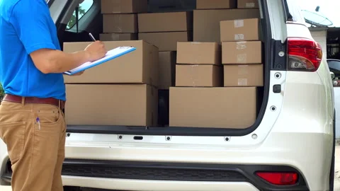 Express delivery man checklist and get cardboard box from car to front of house Stock Footage 136415911