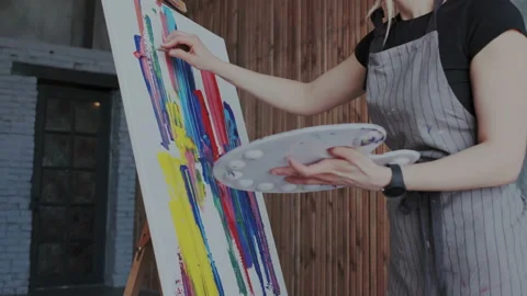 Express your creativity. Positive young woman drawing on easel while enjoying Stock Footage 106125727