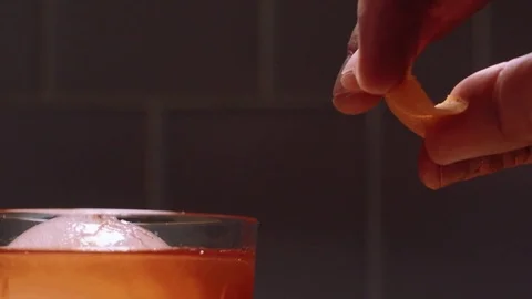 Expressing an orange peel on an old fashioned Stock Footage 83862599