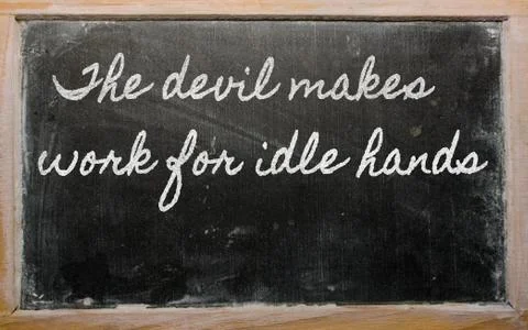 Expression -  the devil makes work for idle hands - written on a school black Stock Photos