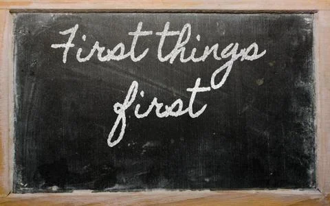 Expression - first things first  - written on a school blackboard with chalk Stock Photos
