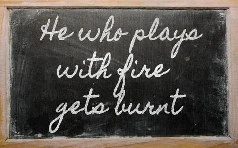 Expression -  he who plays with fire gets burnt - written on a school blackbo Stock Photos
