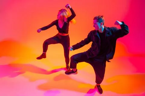 Expression. Two beautiful stylish hip-hop dancers on colorful gradient Stock Photos