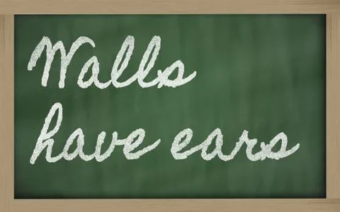 Expression -  walls have ears - written on a school blackboard with chalk Stock Photos