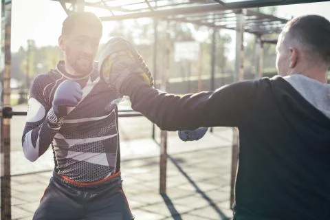 Expressive boxer mastering punches while training with focus mittens Stock Photos
